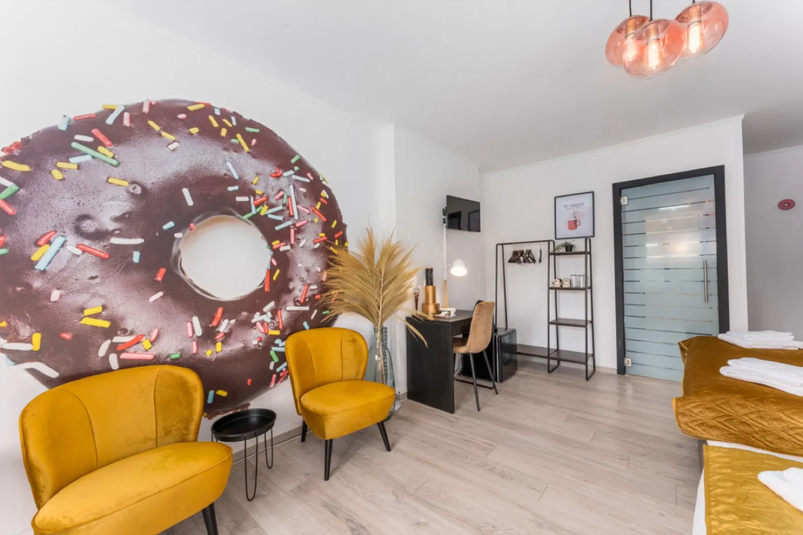Two mustard armchairs in front of a floor-to-ceiling chocolate donut with sprinkles