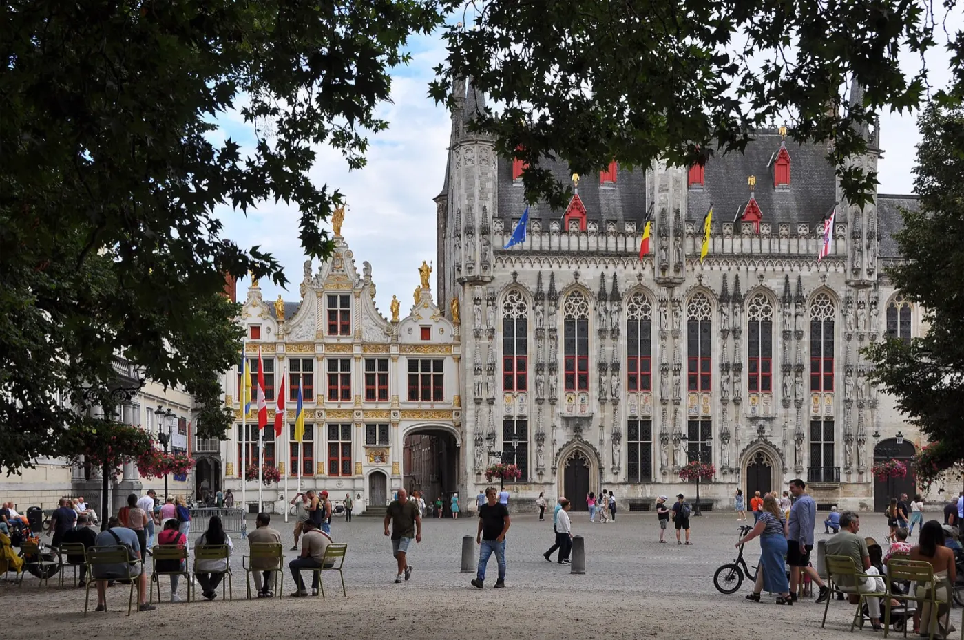 The Burg square with the Gothic city hall, flags and people on benches