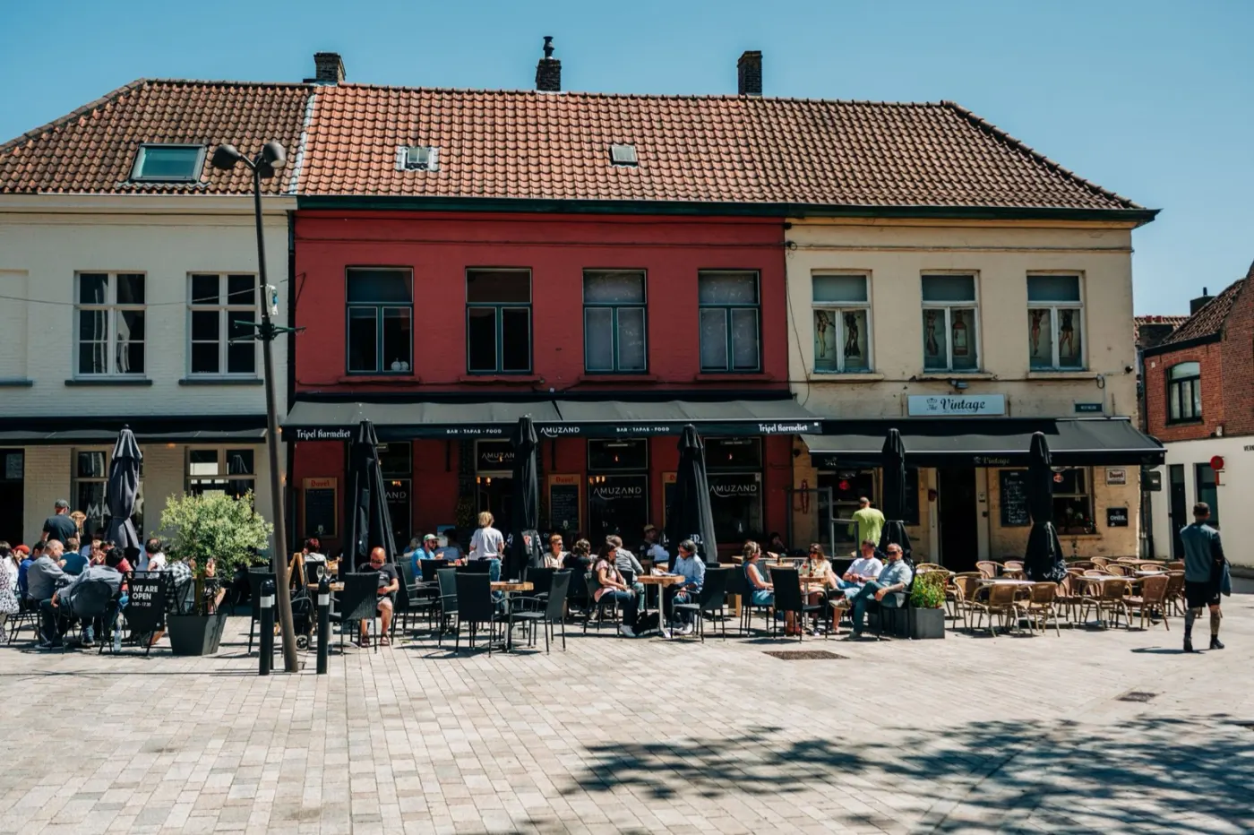 People eating on a sunny café terrace in Bruges